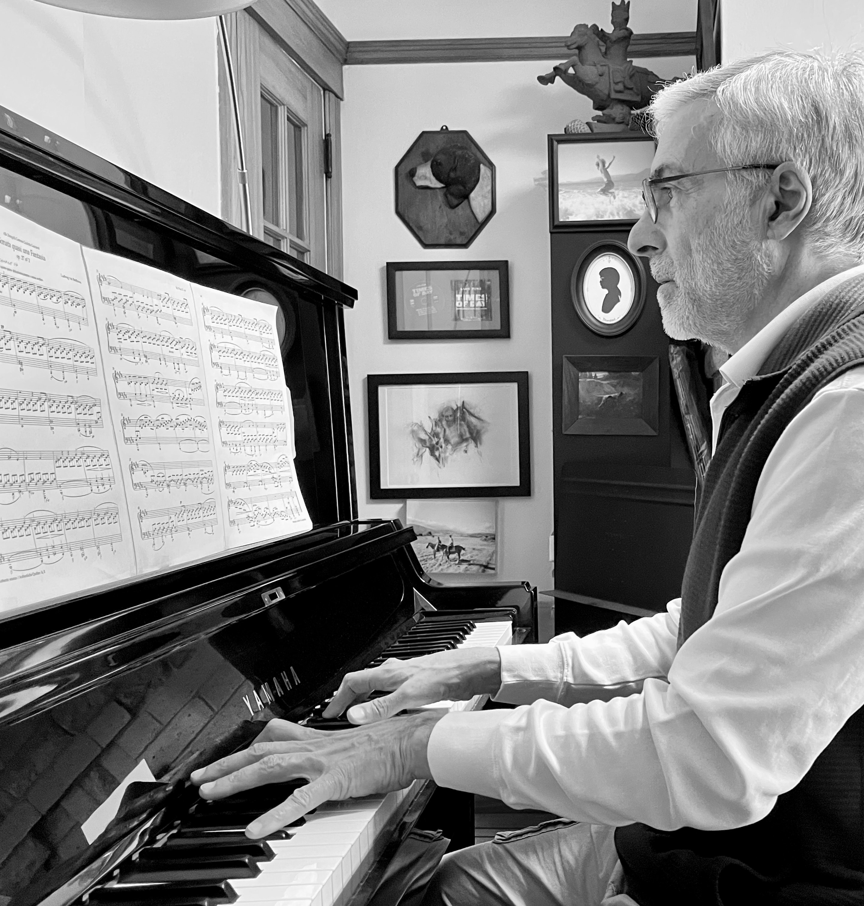 Luis Pine playing piano beside sheet music