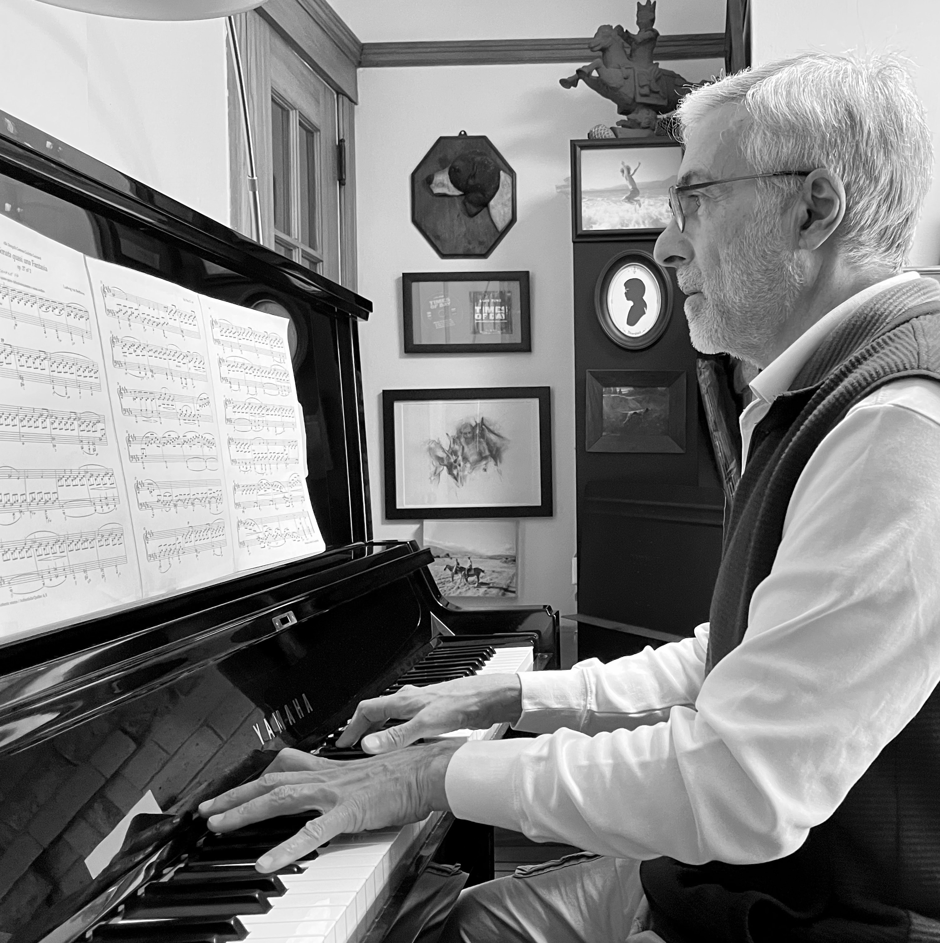 Luis Pine playing piano beside the Times of Day score